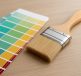 A paintbrush resting next to a color palette on a wooden surface.